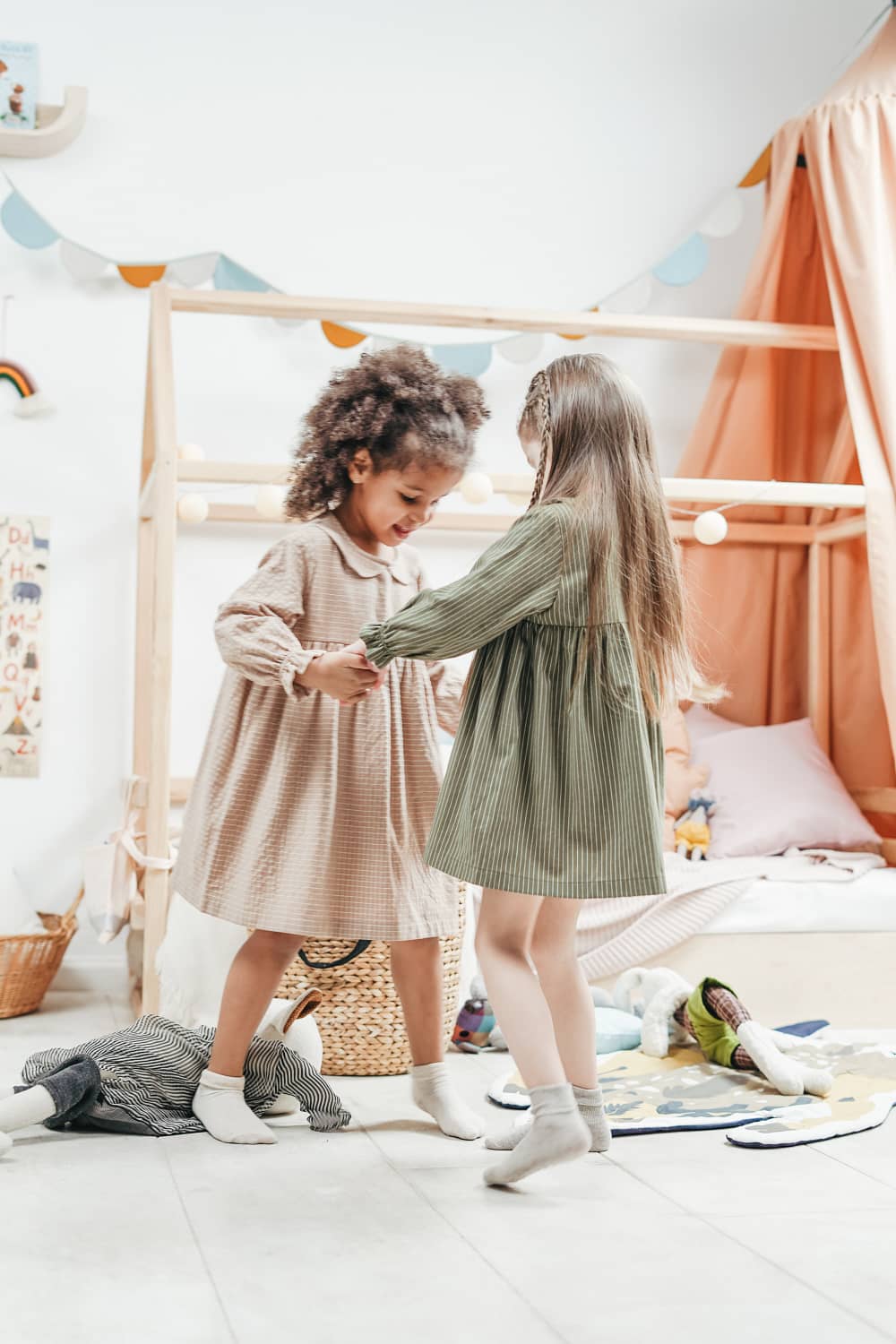 2 small girls dancing on a bed, holding each other hands