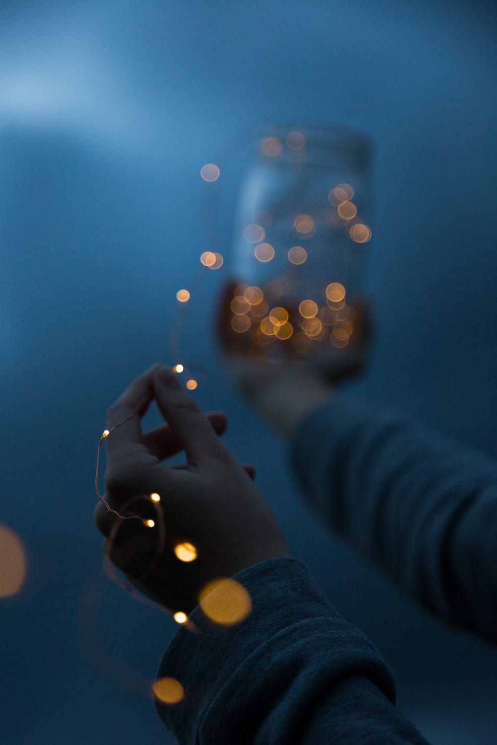 woman holding a yellow string light and a glass