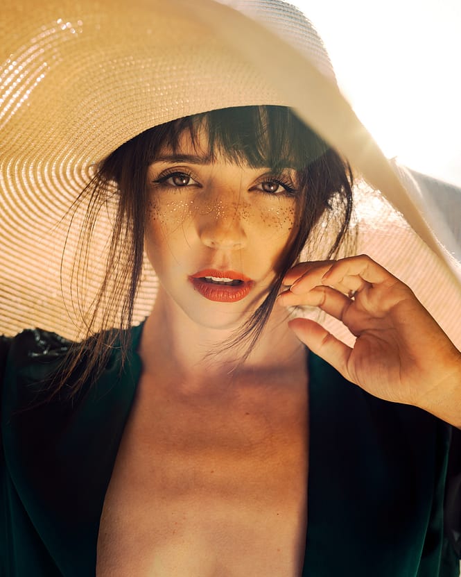 Beautiful woman in green dress with a straw hat covering her dark hair